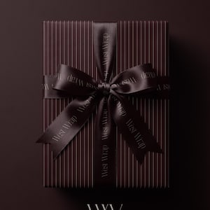 Puede incluir: Una caja de regalo rectangular envuelta en papel marrón oscuro con finas rayas verticales. La caja está atada con una cinta de satén marrón oscuro que presenta el texto repetido West Wrap en una fuente clara, atada en un lazo en el centro.