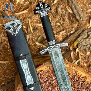 Può includere: Un pugnale in acciaio di Damasco con manico nero e dettagli in metallo argentato con intricati motivi a intreccio. Il pugnale include un fodero nero abbinato con finiture in metallo argentato e un avvolgimento in corda nera.