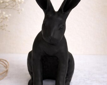May include: A matte black rabbit figurine with long ears and a seated pose. The sculpture is a solid color and has a smooth finish. The rabbit is a decorative item, suitable for home decor.