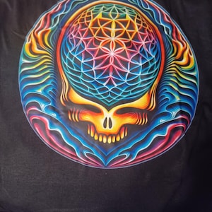 May include: Black t-shirt featuring a vibrant, psychedelic design of a skull with a geometric pattern. The skull is rendered in a spectrum of colors, including blue, red, yellow, and orange, with a detailed, symmetrical design.