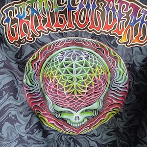 May include: A dark gray fabric with a swirling pattern, featuring a colorful graphic of a skull with a geometric design and the text "Grateful Dead" in a rainbow font.