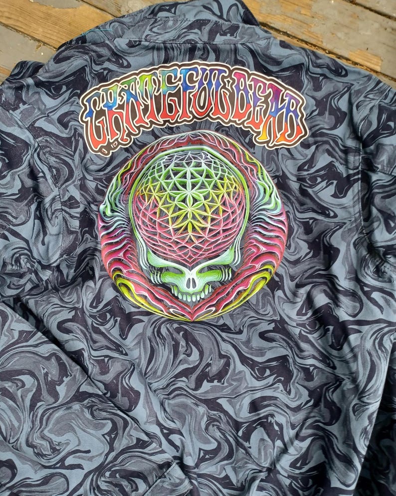 May include: A button-up jacket with a swirling gray and black pattern. The back features a colorful graphic of a skull with a geometric design and the text "Grateful Dead" in rainbow colors.