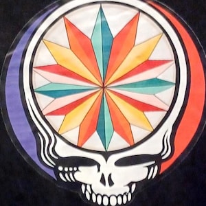 May include: A colorful graphic design featuring a stylized skull with a starburst design. The starburst is composed of various colors, including red, orange, yellow, and teal. The skull is white with black outlines, set against a black background.