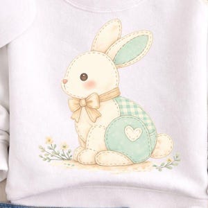 Op de afbeelding: Witte sweatshirt met een aquarel illustratie van een konijn met een strik en een geruit patroon. De afbeelding bevat een witte baseball cap, een blauwe jeans en witte sneakers. De tekst op de afbeelding luidt "Digital Download PNG File No Physical Item."