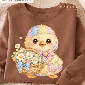 May include: A brown sweatshirt featuring a colorful cartoon chick holding a basket of flowers. The chick has a patchwork design with pastel colors and a large bow. The text "PNG File | Digital Download" is in the top left corner.