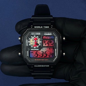 Puede incluir: Un reloj digital negro Casio World Time con un gráfico personalizado de Spider-Man en la esfera circular, un patrón de telaraña roja en la pantalla y texto que incluye World Time, Illuminator y 10 Year Battery en la cara rectangular.