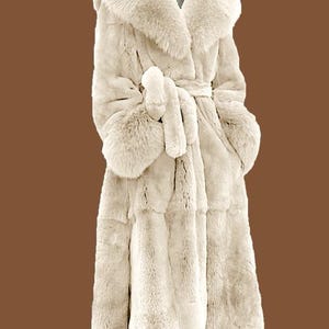 May include: Cream-coloured faux fur coat featuring a large collar, long sleeves, and a matching belt. The coat has a knee-length hemline and a soft, textured appearance. The coat is designed for warmth and style.
