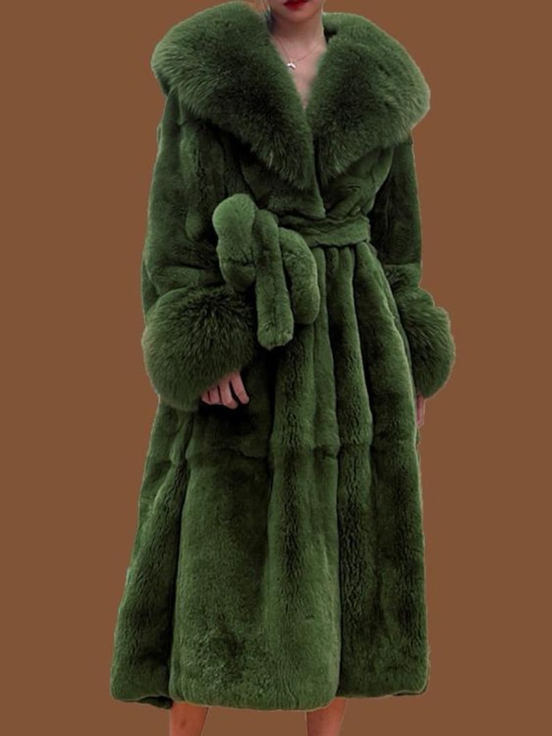 May include: An olive green faux fur coat with a large collar, cuffs, and a matching belt. The coat has a plush texture and a flowing silhouette. This long coat is designed to be worn as outerwear, offering a luxurious look.