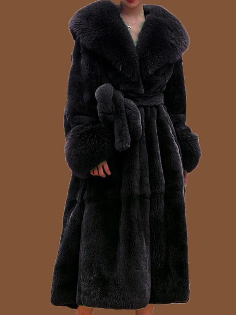 May include: A full-length black faux fur coat with a large collar and cuffs. The coat is belted at the waist with a matching tie. The coat has a luxurious appearance, suitable for formal wear. The coat is floor-length.