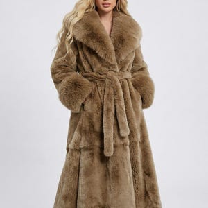 May include: A long, brown faux fur coat featuring a wide collar, long sleeves, and a matching belt. The coat has a tiered design and is knee-length, offering a luxurious and warm aesthetic. The coat is designed for cold weather.
