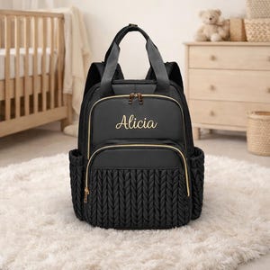 Black personalized diaper backpack with embroidered name Alicia in modern baby nursery