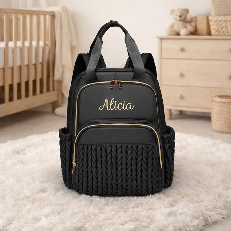 Black personalized diaper backpack with embroidered name Alicia in modern baby nursery