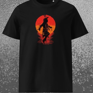 Könnte beinhalten: Schwarzes T-Shirt mit einer Silhouette eines indianischen Tänzers vor einem roten und orangen Sonnenuntergang. Der Text "Realm of Mythology" ist am unteren Rand des T-Shirts aufgedruckt.