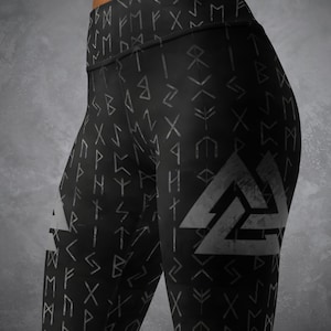 May include: Black leggings with a repeating pattern of gray runes and a large gray Valknut symbol on the side. The leggings are high-waisted and form-fitting, made of a stretchy material.