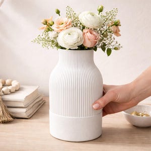 May include: A set of three ceramic mugs with a speckled, matte finish. The mugs are in shades of cream, light gray, and dark gray. Each mug has a simple, minimalist design and a rounded handle.