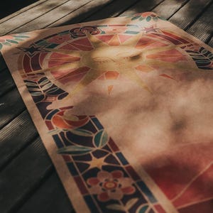 May include: A yoga mat featuring a sun design in yellow, orange, red, and blue. The mat has a stained glass style border with floral and star motifs. The mat is laid out on a wooden deck.