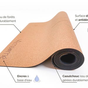 May include: A rolled yoga mat made from cork and rubber. The mat is light brown with the brand name "Amsm&eacute;" printed on it. The text on the mat indicates it is made from sustainably managed forests and has a soft, non-slip surface.