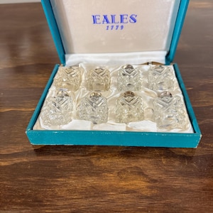 May include: A white ceramic mug with a black handle and the text "But First, Coffee" in a bold, black font. The mug is displayed on a white surface. The mug is approximately 4 inches tall.