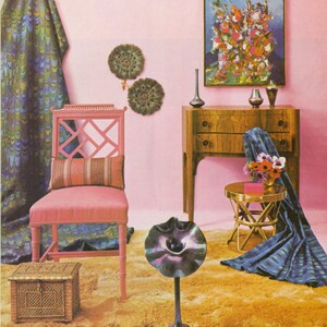 May include: A retro-style interior scene with a pink wall, featuring a pink chair, a wooden dresser, and a small gold table. The room is decorated with a patterned curtain, artwork, and decorative objects, creating a vintage aesthetic.