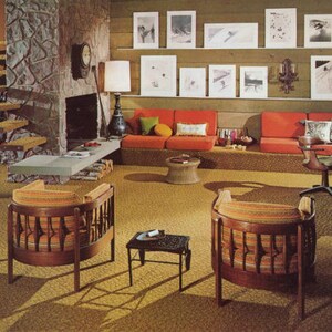 May include: A retro living room with orange seating, wooden chairs, and a stone fireplace. Artwork hangs on the wall above the sofa. The room has a vintage aesthetic with a shag carpet and a small side table.