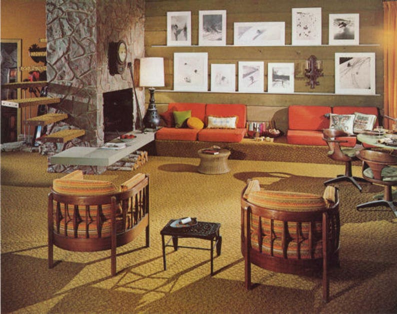 May include: A retro living room with orange seating, wooden chairs, and a stone fireplace. Artwork hangs on the wall above the sofa. The room has a vintage aesthetic with a shag carpet and a small side table.