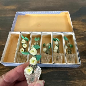 May include: A white ceramic mug with a black handle and the text "But First, Coffee" in a black, bold font. The mug is on a wooden surface. The mug is 10 cm tall.