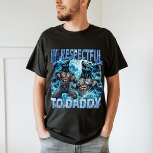 May include: Black t-shirt featuring a graphic of two werewolves with blue lightning and the text "BE RESPECTFUL TO DADDY" in blue. The werewolves are ripping open their shirts. The shirt is made of a soft material.
