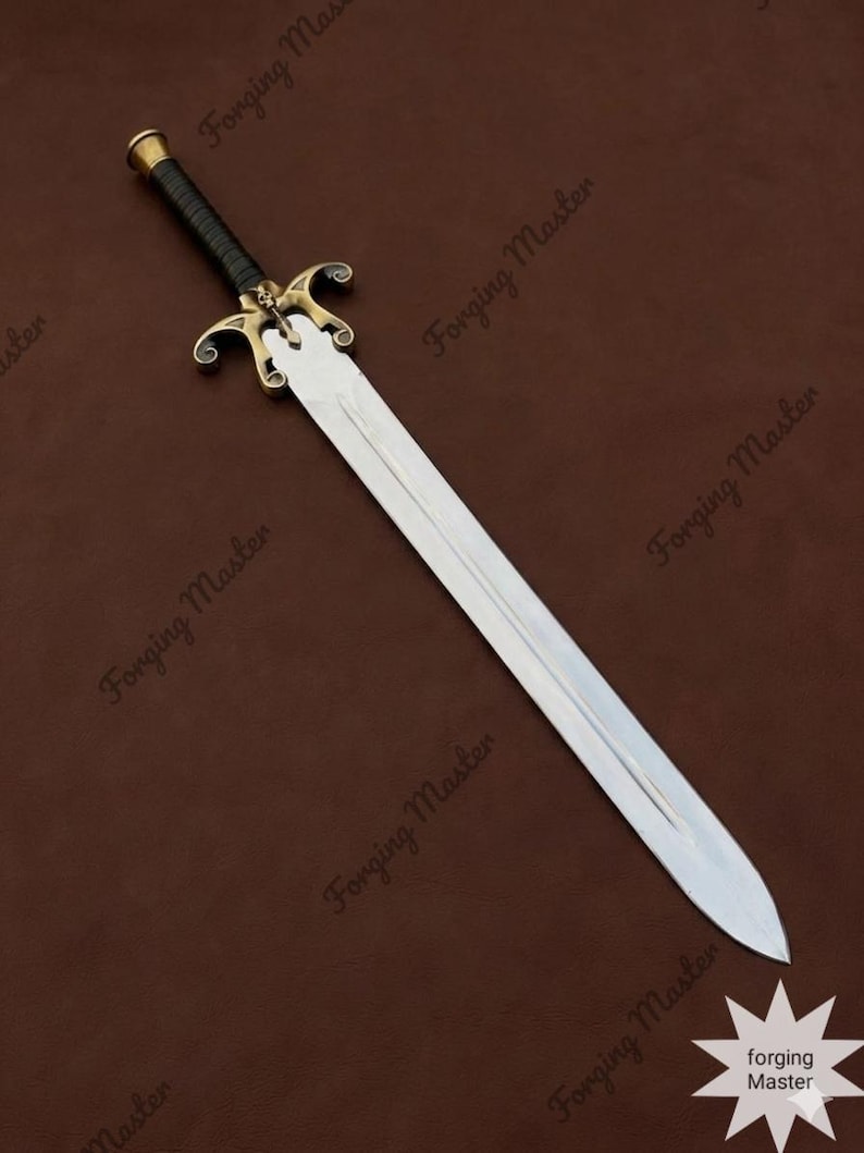 May include: A double-edged steel sword featuring a central fuller, a brass crossguard with ornate scrollwork and a central skull motif, and a black leather-wrapped grip with a brass pommel. The blade is polished and tapers to a sharp point.