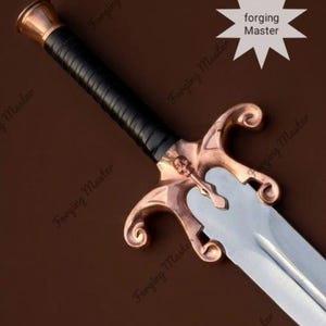 May include: A sword featuring a silver-toned blade, a black wrapped handle, and a copper-colored crossguard with a skull emblem. The crossguard has curved, scroll-like ends. The text Forging Master is visible on the blade and background.