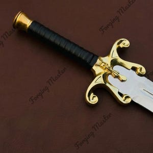 May include: A sword featuring a silver-toned blade, a black wrapped handle, and a gold-toned crossguard with a skull emblem. The pommel is gold-toned and cylindrical. The text Forging Master is visible multiple times across the image.