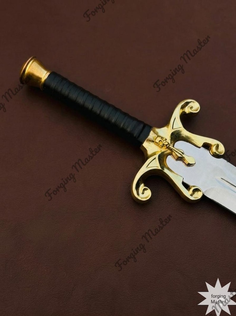 May include: A sword featuring a silver-toned blade, a black wrapped handle, and a gold-toned crossguard with a skull emblem. The pommel is gold-toned and cylindrical. The text Forging Master is visible multiple times across the image.