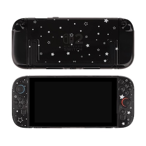 May include: Black Nintendo Switch console with a starry design. The console features a black screen and controllers with white star accents. The back of the console has the Nintendo Switch logo and additional star patterns.