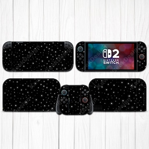 May include: A black Nintendo Switch console and accessories with a starry night design. The set includes the console, Joy-Con controllers, and a dock, all featuring a pattern of white stars on a black background. The Nintendo Switch screen displays the Nintendo Switch logo.