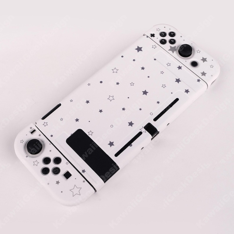 May include: White Nintendo Switch case with a pattern of gray stars and dots. The case has black buttons and control sticks. The design covers the entire case, including the buttons and the back.