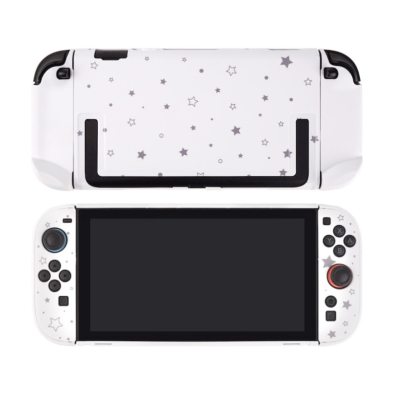 May include: White gaming console with a black screen and a white back with a gray star pattern. The console has black accents and buttons with a red joystick. The top part of the console is also white with a gray star pattern.