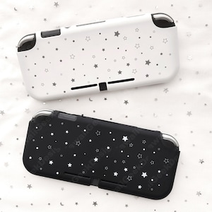 May include: Two protective cases for a gaming console, one white and one black. Both cases are decorated with a pattern of small, gray stars. The cases have cutouts for buttons and ports.
