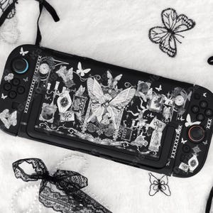 Può includere: Una skin nera per console di gioco portatile con un dettagliato disegno a linee bianche di farfalle, cornici ornamentali, orologi e flaconi di profumo vintage che copre l'intera superficie e le sezioni dei controller.