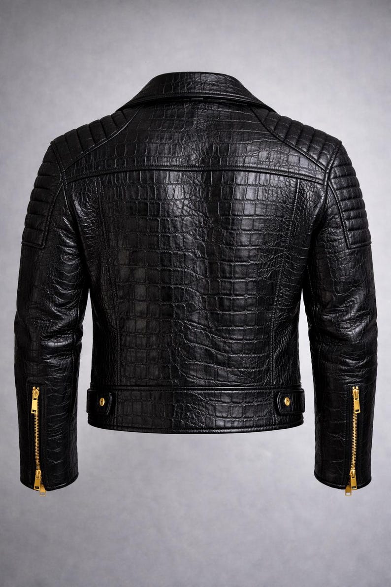 May include: Black leather jacket with a textured, crocodile-like pattern. Features a classic collar, quilted shoulder detailing, and gold-toned zippers on the sleeves. The jacket has a tailored fit and a sleek, modern design.