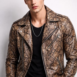 Może przedstawiać: Brązowa i beżowa skórzana kurtka ze wzorem skóry węża, srebrnym zamkiem błyskawicznym i czarną koszulką. Kurtka ma klasyczny styl motocyklowy z kołnierzem z klapami i srebrnym naszyjnikiem.