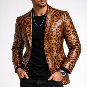 以下が含まれることがあります： ノッチドラペル付きの茶色と黒のヒョウ柄ブレザー。ジャケットは黒いシャツの上に着用し、黒いジーンズと合わせています。シルバーのチェーンネックレスとシルバーの腕時計がルックを完成させています。
