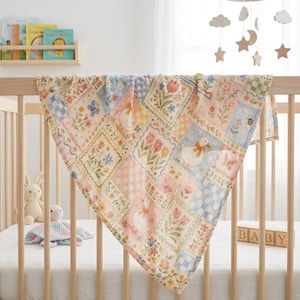 Puede incluir: Una manta para beb&eacute; de colores pastel con un dise&ntilde;o de patchwork con motivos florales y de patos. La manta, con su suave textura acolchada, est&aacute; sobre una cuna de madera. La paleta de colores incluye rosa, azul, amarillo y verde.