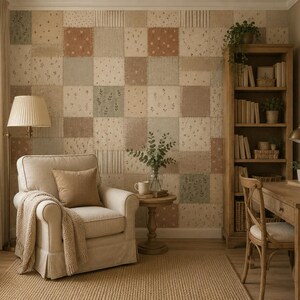May include: A room featuring a wall covered in a patchwork wallpaper with square patterns in muted tones of beige, sage green, and terracotta. The space includes a beige armchair with a throw blanket, a wooden desk, a bookshelf, and a floor lamp.