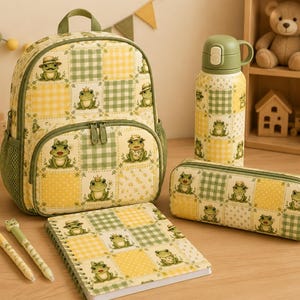 May include: A backpack, a water bottle, a pencil case, and a spiral notebook, all featuring a matching yellow and green checkered pattern with illustrations of frogs. Two pens with frog toppers are placed next to the notebook.