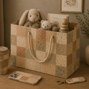 May include: A rectangular paper gift bag with a patchwork floral pattern in muted beige, brown, and green tones, featuring cream rope handles. Inside are a plush rabbit, two teddy bears, a wooden stacking toy, and a book titled The Tale of.