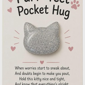 May include: A silver glittery cat-shaped token attached to a cream-colored card. The card features the text "Purr-fect Pocket Hug" and a poem: "When worries start to sneak about, And doubts begin to make you pout, Hold this kitty nice and tight, And know that everything's alright."