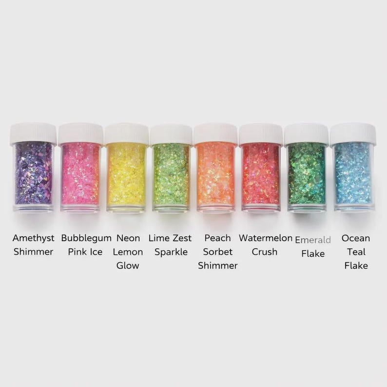May include: Eight small clear jars filled with colorful glitter. The glitter colors include purple, pink, yellow, green, orange, red, green, and blue. Each jar has a white lid. Text below each jar identifies the glitter color.