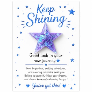 May include: A purple glittery star-shaped resin ornament attached to a white card featuring blue text that reads Keep Shining, Good luck in your new journey, and You've got this, surrounded by blue star illustrations and small blue hearts.