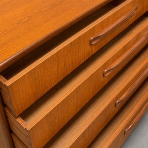 May include: A wooden dresser with four open drawers. The dresser is made of light brown wood with a smooth finish. Each drawer has a curved handle. The drawers are partially pulled out, revealing the interior.