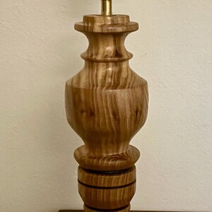 May include: A wooden table lamp with a turned wood base and a brass lamp holder. The lamp has a classic design with a dark brown finish. The lamp is approximately 18 inches tall.