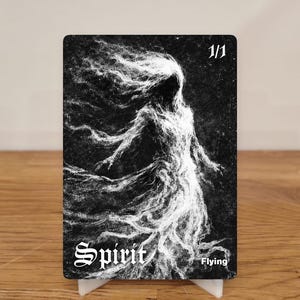 Könnte beinhalten: Schwarz-weiße Karte mit einer geisterhaften Figur mit fließendem Haar. Das Wort "Spirit" ist in einer gotischen Schrift geschrieben, darunter "Flying". Die Karte zeigt auch "1/1". Die Karte ist auf einem weißen Ständer aufgestellt.